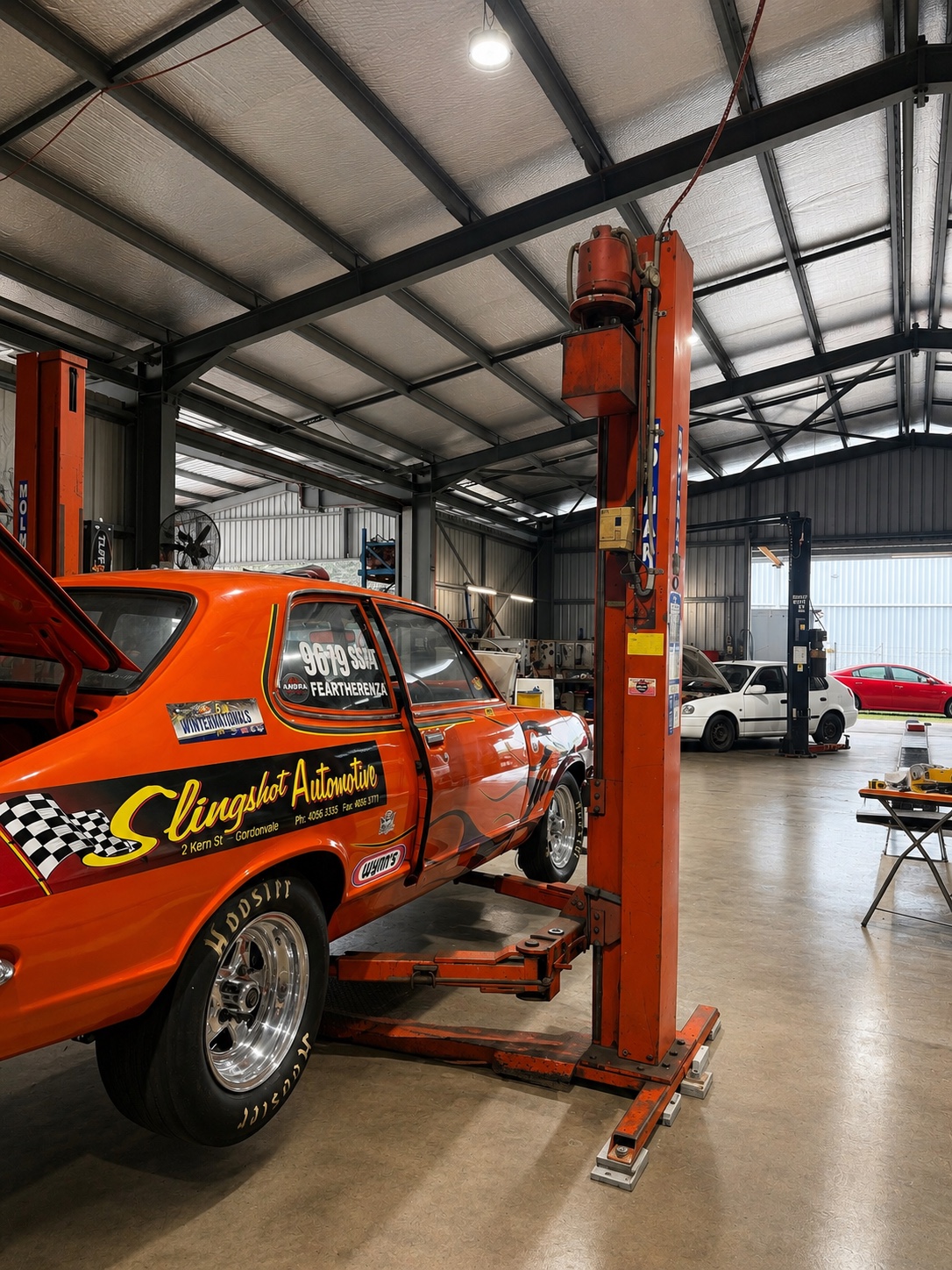 The Slingshot Automotive Torana drag car up on a hoist inside the workshop